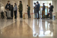 Journalists line up for copies of a Chinese government-produced report titled "Democracy that Works" before a press conference at the State Council Information Office in Beijing, Saturday, Dec. 4, 2021. China's Communist Party took American democracy to task on Saturday, sharply criticizing a global democracy summit being hosted by President Joe Biden next week and extolling the virtues of its governing system. (AP Photo/Mark Schiefelbein)