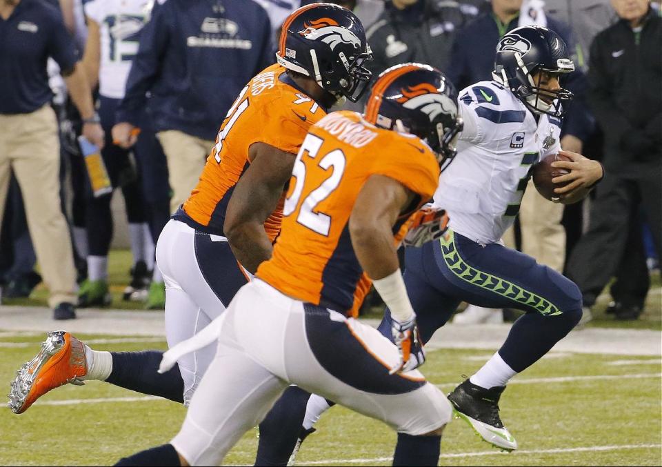 Seattle Seahawks quarterback Russell Wilson (3) runs against Denver Broncos defensive end Robert Ayers (91) and middle linebacker Wesley Woodyard (52) during the first half of the NFL Super Bowl XLVIII football game Sunday, Feb. 2, 2014, in East Rutherford, N.J. (AP Photo/Matt York)