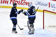 Winnipeg Jets' goaltender Connor Hellebuyck (37) celebrates the win over the Seattle Kraken with Dylan DeMelo (2) after an NHL hockey game in Winnipeg, Manitoba on Tuesday April 16, 2024. (Fred Greenslade/The Canadian Press via AP)