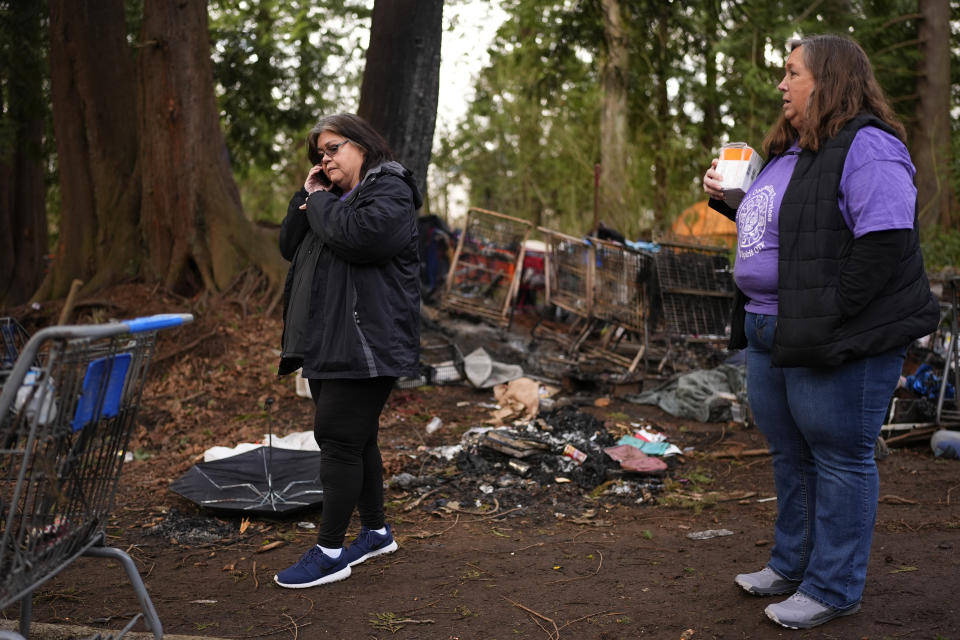 Evelyn Jefferson, a crisis outreach supervisor for Lummi Nation, takes a phone call while standing with nurse Kim Long, right, as they check on tribal members living at a longstanding homeless encampment near Walmart, Thursday, Feb. 8, 2024, in Bellingham, Wash. The Lummi Nation declared a state of emergency due to the fentanyl crisis in 2022. Washington State tribal leaders are urging state lawmakers to pass a bill that would send at least $7.75 million in funding to tribal nations to help them stem a dramatic rise in opioid overdose deaths. (AP Photo/Lindsey Wasson)