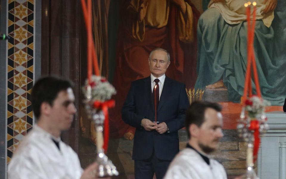 Russian president Vladimir Putin was ashen-faced as he held a candle during the Orthodox Easter mass on April 24 - Contributor/Getty Images