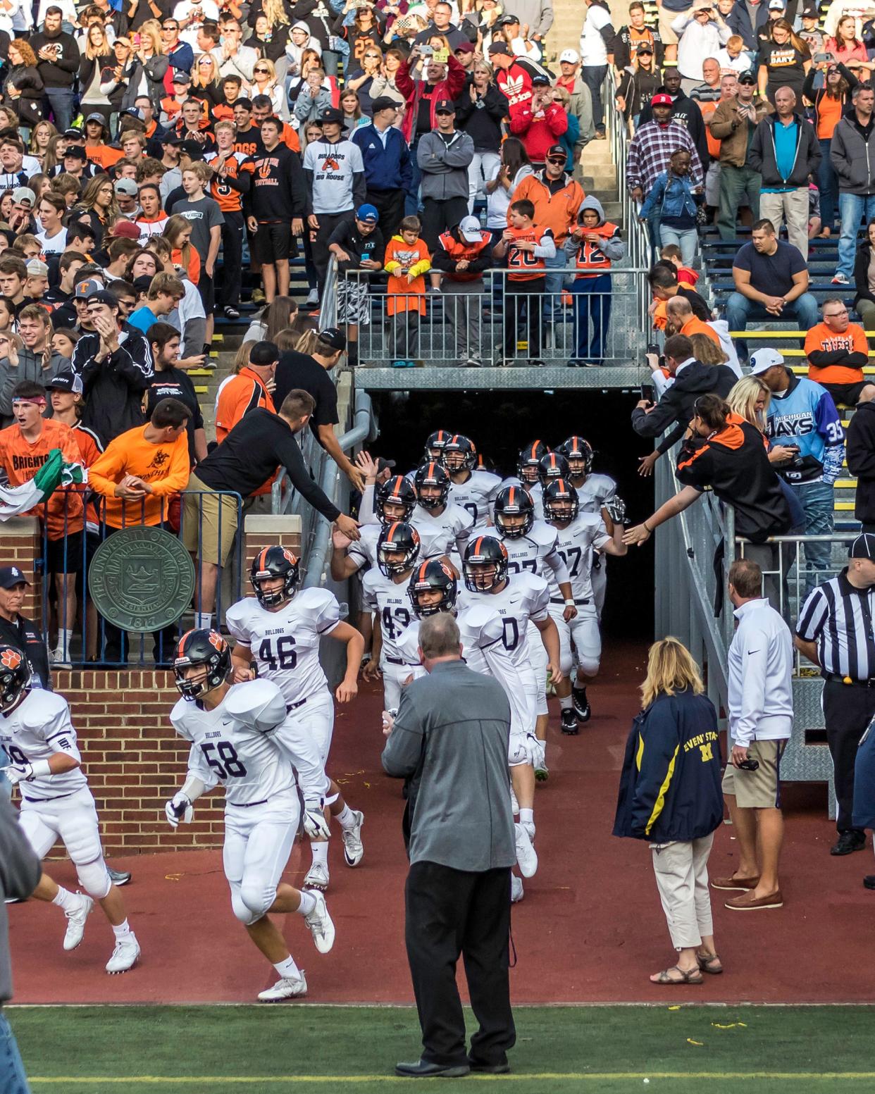 Brighton football players come out of the tunnel at Michigan Stadium for the 2017 season opener against Belleville.