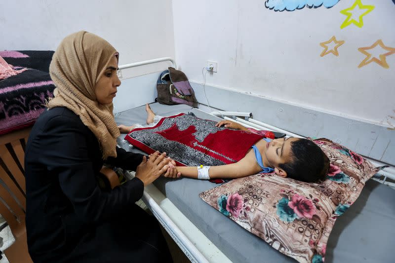 Palestinian boy Mohammed Imad, who was wounded in Israeli fire, is looked after by his mother as he lies on a bed at Al-Aqsa hospital in Deir Al-Balah in the central Gaza Strip