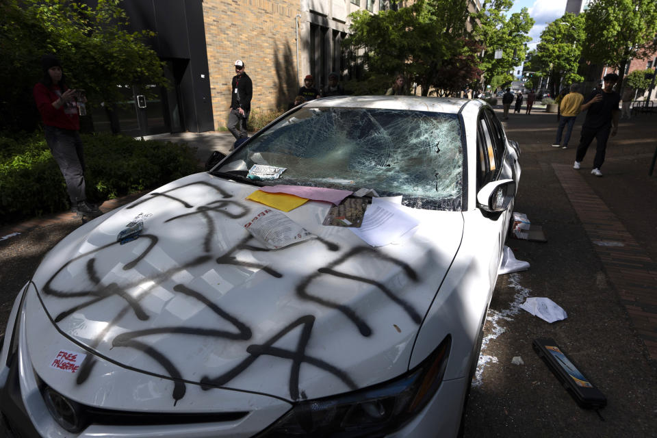 A car that attempted to drive through a crowd of pro-Palestinian protesters on the Portland State University campus is seen parked and damaged on a campus walkway on Thursday, May 2, 2024, in Portland, Ore. After the driver fled on foot the protesters damaged the car. (AP Photo/Jenny Kane)