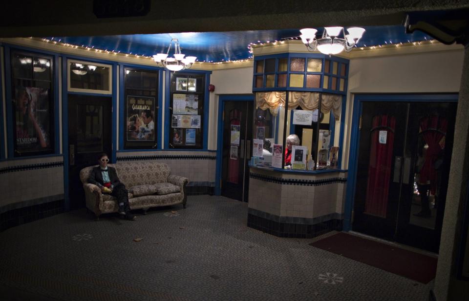 Cinema owner Ann Nelson sits in the ticket booth prior to the evening show, while a customer waits for a friend. (Reuters)