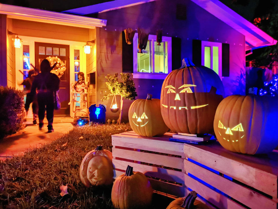 Kids trick-or-treating on Halloween night in suburban Californian house decorated with jack o' lantern pumpkin