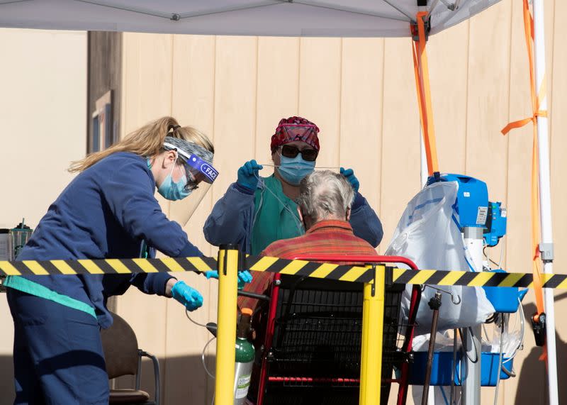 Healthcare workers attend to a patient as St. Mary Medical Center resorts to using triage tents outside in California