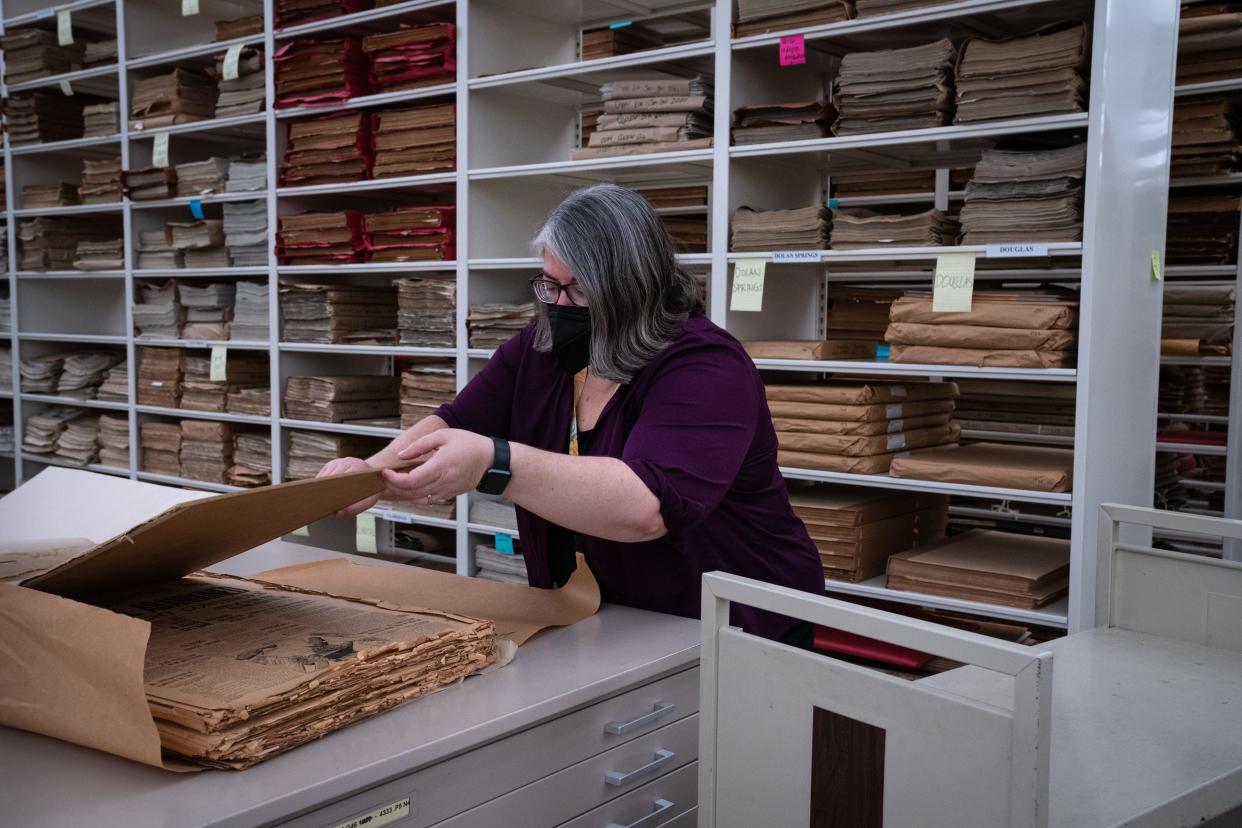 Korina Tueller unwraps copies of the Nogales Herald on Oct. 13, 2022, in a climate control pod at the Arizona State Library Archives in Phoenix.