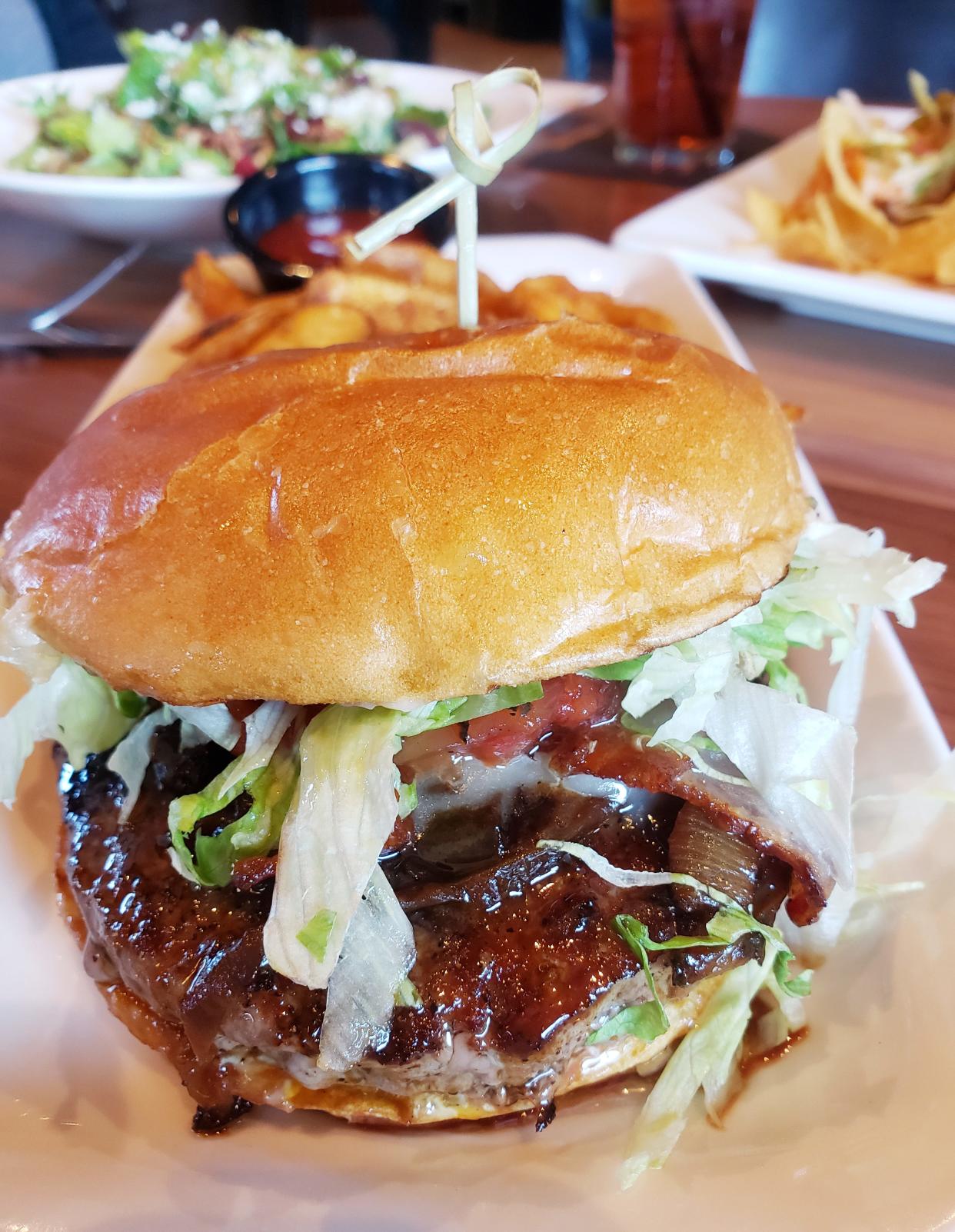 Bru Burger Bar opened Monday in Bloomington, where burgers, like this one topped with cheese, bacon, tomato jam, caramelized onions, chopped lettuce and mayo, are on the menu.