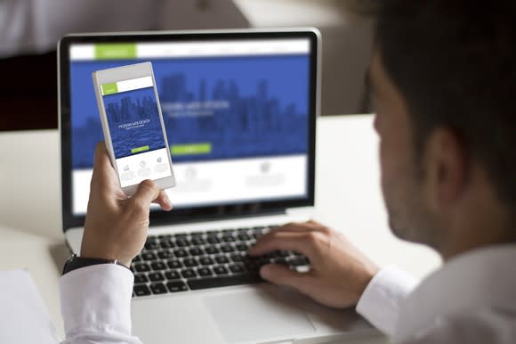 Man at desk looking at website design on a laptop.