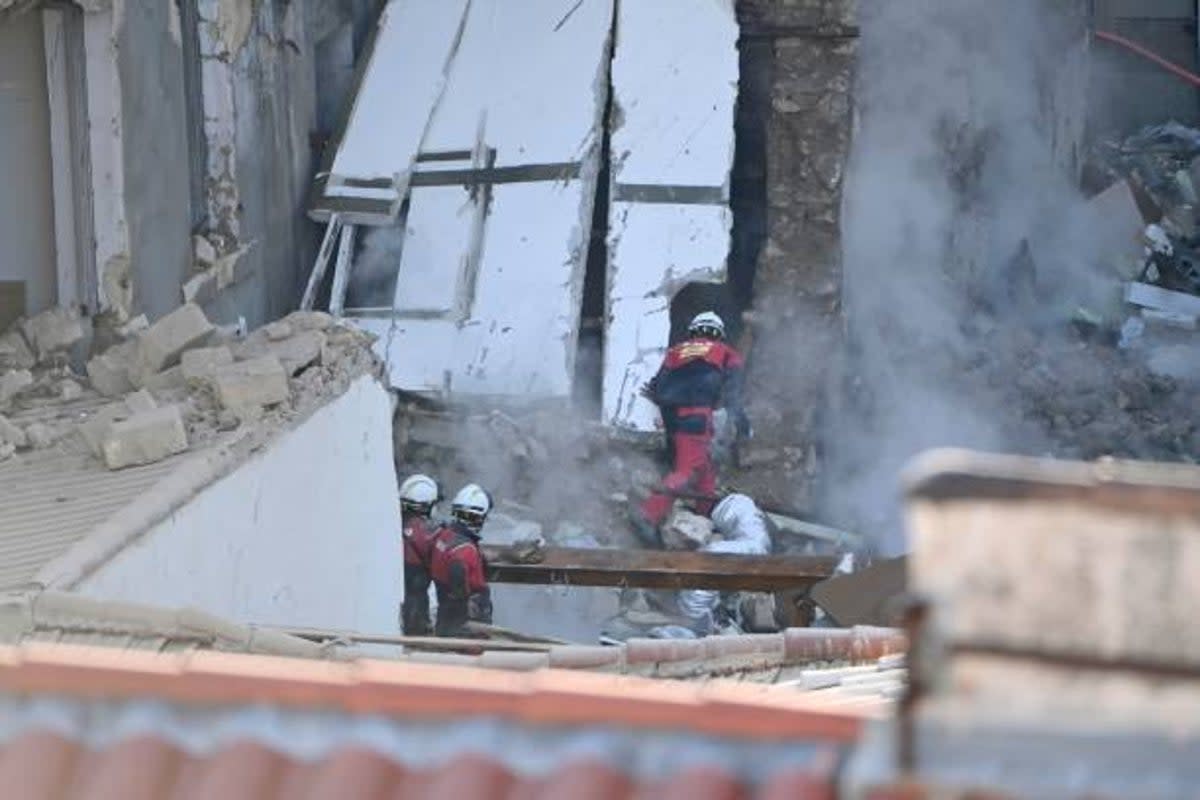 A dog handler peers into a destroyed building at ‘rue Tivoli’ after a building collapsed in the street, in Marseille, southern France, on 9 April 2023 (AFP via Getty Images)