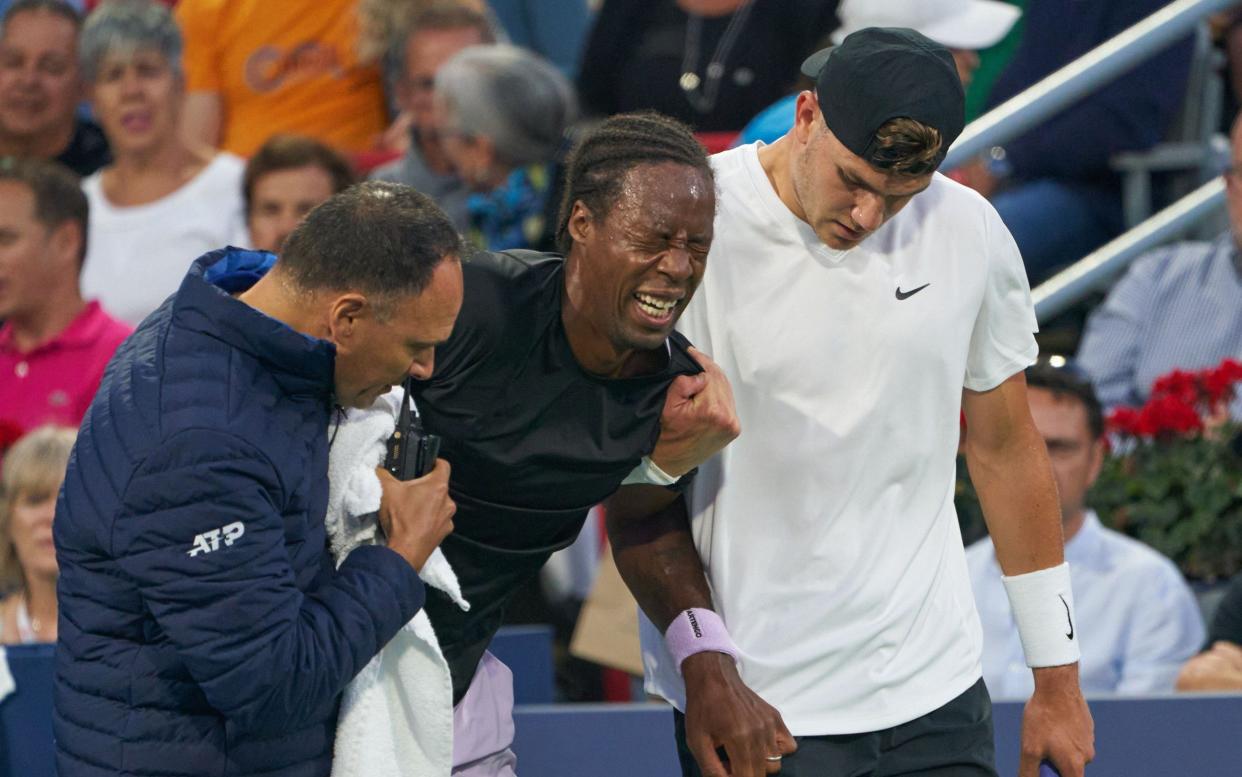 Draper, right, helps Monfils off the court in Montreal - EPA