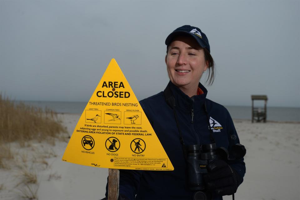 Rising piping plover numbers in Massachusetts are a testament to conservation efforts, Massachusetts Audubon Society Coastal Waterbird Program Director Lyra Brennan said. Brennan stands on Jan. 19 with a shorebird closure sign at Seagull Beach in West Yarmouth. The signs are typically placed on beaches each spring.