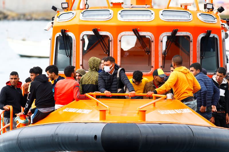 Migrants wait to disembark from a Spanish coast guard vessel in the port of Arguineguin