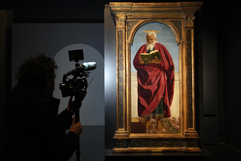 A cameraman films the Italian artist Piero della Francesca's St. John the Evangelist painting on the occasion of the inauguration of the exhibit "Piero della Francesca. Il Polittico Agostiniano riunito" (Piero della Francesca. The Augustinian Polyptych reunited) at Milan's Poldi Pezzoli museum, Italy, Tuesday, March 19, 2024. The Augustinian altarpiece originally comprised 30 sections in a polyptych, was dismantled after the Augustinians moved churches and eventually sold off. Only eight of the sections remain as individual paintings owned by museums in New York, Washington, D.C., London, Milan and Lisbon, Portugal. (AP Photo/Antonio Calanni)