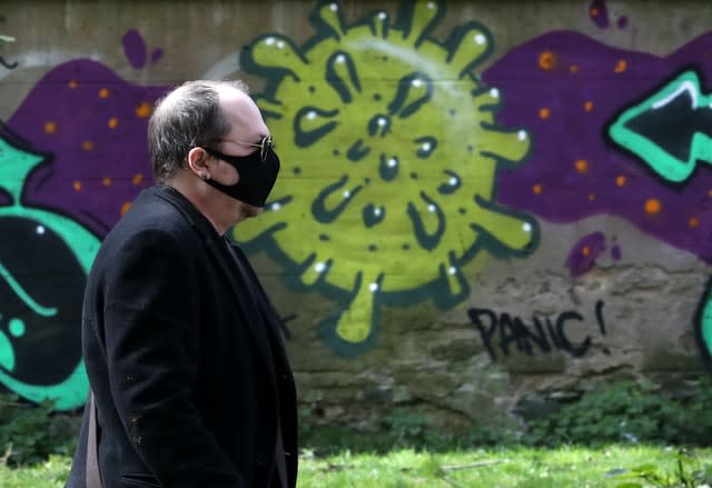 A man wearing a mask walks past coronavirus-related graffiti in Edinburgh