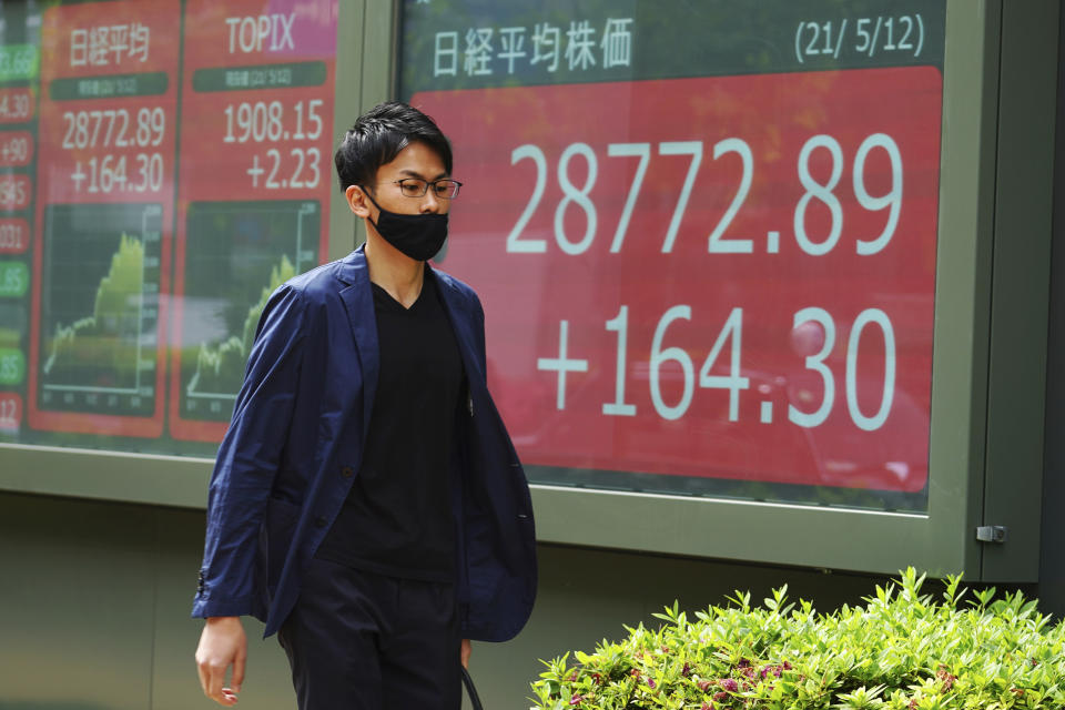 A man wearing a protective mask walks in front of an electronic stock board showing Japan's Nikkei 225 index at a securities firm Wednesday, May 12, 2021, in Tokyo. Asian stock markets retreated Wednesday as investors looked ahead to U.S. data they worry will show inflation is picking up.(AP Photo/Eugene Hoshiko)