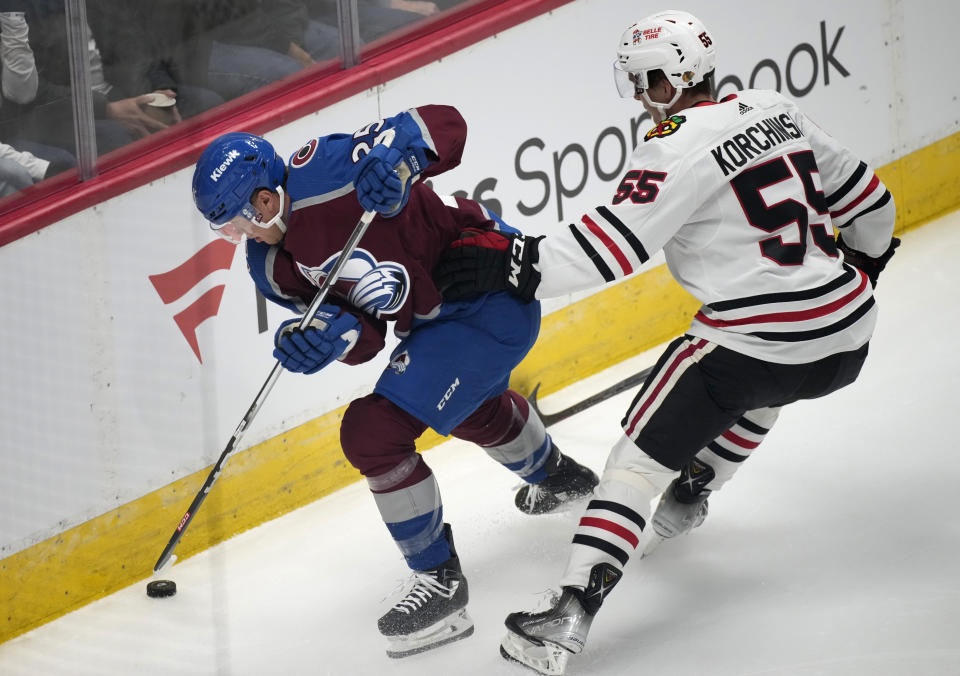 Colorado Avalanche right wing Logan O'Connor, left, battles to control the puck as Chicago Blackhawks defenseman Kevin Korchinski covers in the first period of an NHL hockey game on Thursday, Oct. 19, 2023, in Denver. (AP Photo/David Zalubowski)