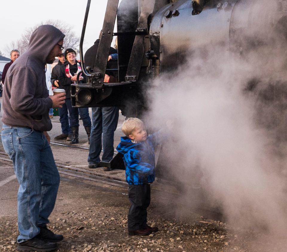 Two-year-old Oliver Crofoot is facinated by the steam produced by the Pere Marquette 1225 steam engine as it idles in the Village of Ashley Sunday, December 6, 2015.