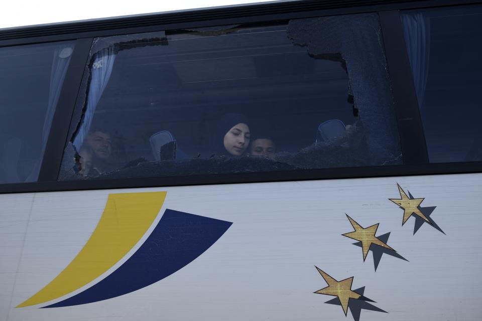 Refugees and migrants look from behind a broken window of a bus as they wait at the toll stations of Malgara, near the Greek port city of Thessaloniki, on Wednesday, Oct. 23, 2019. Protesting local residents in northern Greece set up roadblocks to try and prevent migrants from settling in the area. The government has promised to expand a network of refugee camps and hotel residence programs on the Greek mainland in an effort to ease severe overcrowding at facilities on islands near the Turkish coast. (AP Photo/Giannis Papanikos)