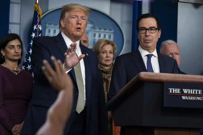 FILE- In this March 17, 2020 file photo Treasury Secretary Steven Mnuchin, right, listens as President Donald Trump speaks during a press briefing with the coronavirus task force, at the White House in Washington. Trump has been telling voters that the U.S. economy will leap back to life “like a rocket,” stronger than ever after its bout with the coronavirus. But there is a reason economics is called the “dismal science.” There are emerging signs that any recovery will fail to match the speed and severity of the economic collapse that occurred in just a few weeks. (AP Photo/Evan Vucci)