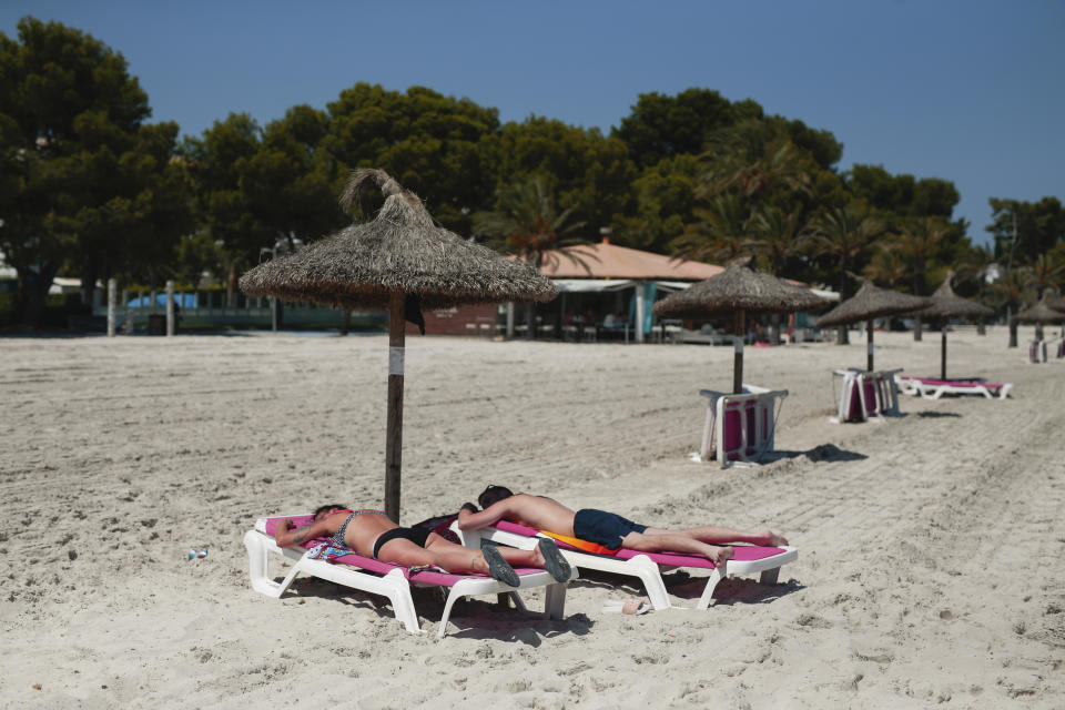 Sunbathers enjoy the beach in Alcúdia, in the Balearic Island of Mallorca, Spain, Tuesday, July 28, 2020. The U.K. government's recommendation against all but essential travel to the whole of Spain means that all travelers arriving in Britain from that country will have to undergo a 14-day quarantine. (AP Photo/Joan Mateu)