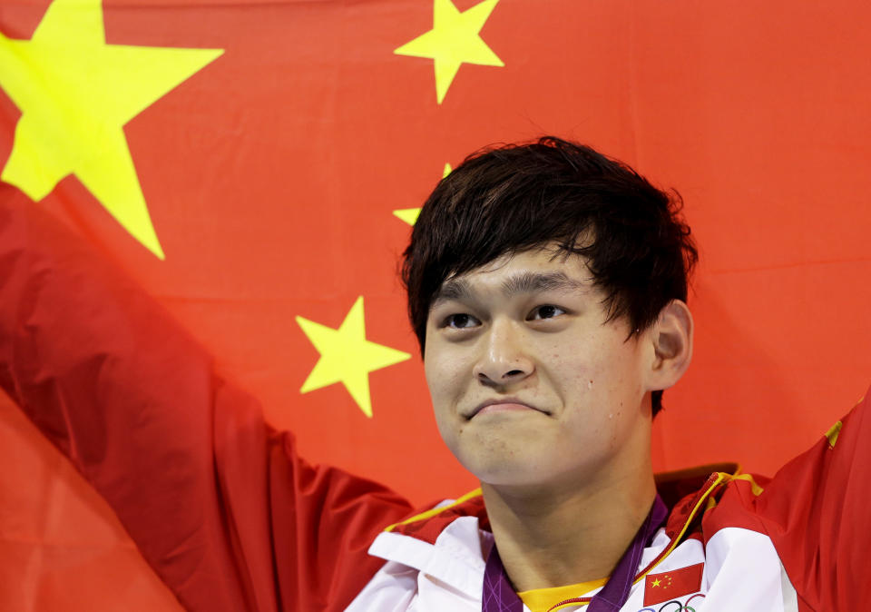 FILE - In this Saturday, Aug. 4, 2012 file photo, China's Sun Yang holds his national flag after winning the gold medal in the men's 1500-meter freestyle swimming final at the Aquatics Centre in the Olympic Park during the 2012 Summer Olympics in London. Chinese swimmer Sun Yang has been banned for eight years for breaking anti-doping rules and will miss the 2020 Tokyo Olympics. (AP Photo/Lee Jin-man, File)