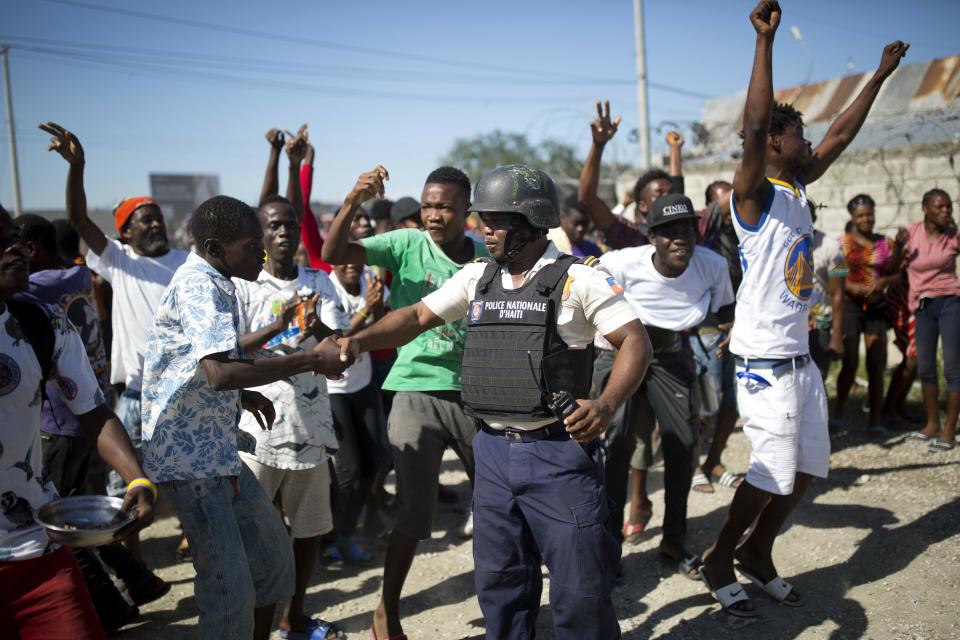 In this Dec. 10, 2018 photo, a resident shakes hands with police inspector Seraphin Frantz after police arrested an alleged gang member whom residents identify as one of the perpetrators of the massacre in the La Saline slum of Port-au-Prince, Haiti. The police are widely seen as corrupt, inefficient and ill-equipped to take on heavily armed gangs that often serve as enforcers of Haiti's fragmented political forces. (AP Photo/Dieu Nalio Chery)