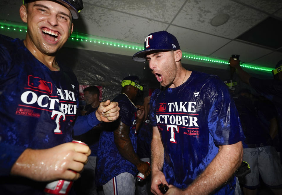 Texas Rangers first baseman Nathaniel Lowe, left, celebrates with teammates after clinching a playoff spot in the American League following a 6-1 win over the Seattle Mariners in a baseball game, Saturday, Sept. 30, 2023, in Seattle. (AP Photo/Lindsey Wasson)