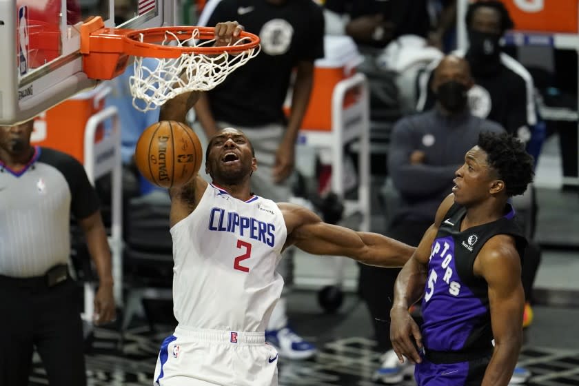 Los Angeles Clippers forward Kawhi Leonard, left, dunks past Toronto Raptors forward Stanley Johnson during the first half of an NBA basketball game Tuesday, May 4, 2021, in Los Angeles. (AP Photo/Marcio Jose Sanchez)