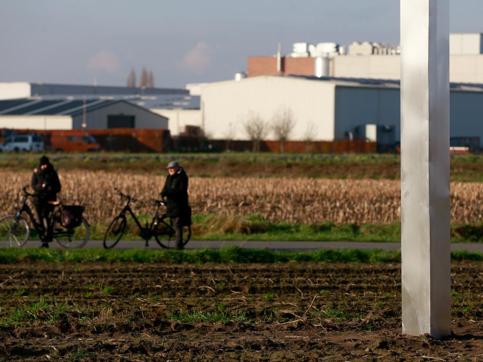 People inspect a metal monolith in a field in Baasrode in Belgium on 8 DecemberEPA