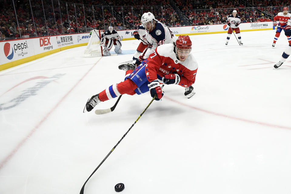 Washington Capitals right wing T.J. Oshie (77) is tripped by Columbus Blue Jackets defenseman Dean Kukan, back, during the second period of an NHL hockey game Friday, Dec. 27, 2019, in Washington. (AP Photo/Nick Wass)