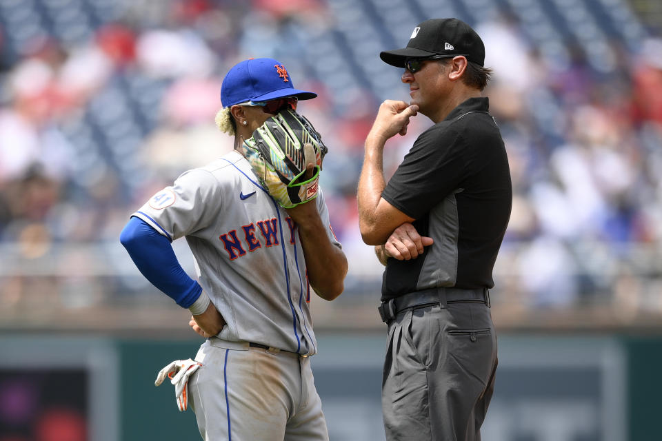 New York Mets shortstop Francisco Lindor, left, chats with second base umpire Chad Fairchild, right, during a pause in the fourth inning of the first baseball game of a doubleheader against the Washington Nationals, Saturday, June 19, 2021, in Washington. This is a makeup of a postponed game from April 1. (AP Photo/Nick Wass)