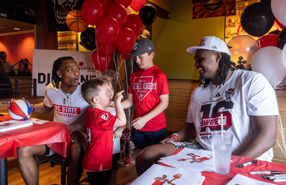 Five-year-old Walker Merritt and NC State’s DJ Burns Jr. share a moment as Burns and DJ Horne, left, sign hundreds of autographs at the Triangle Town Center Applebee’s in Raleigh on Tuesday, April 2, 2024 ahead of the Wolfpack’s Final Four game on Saturday. Travis Long/tlong@newsobserver.com