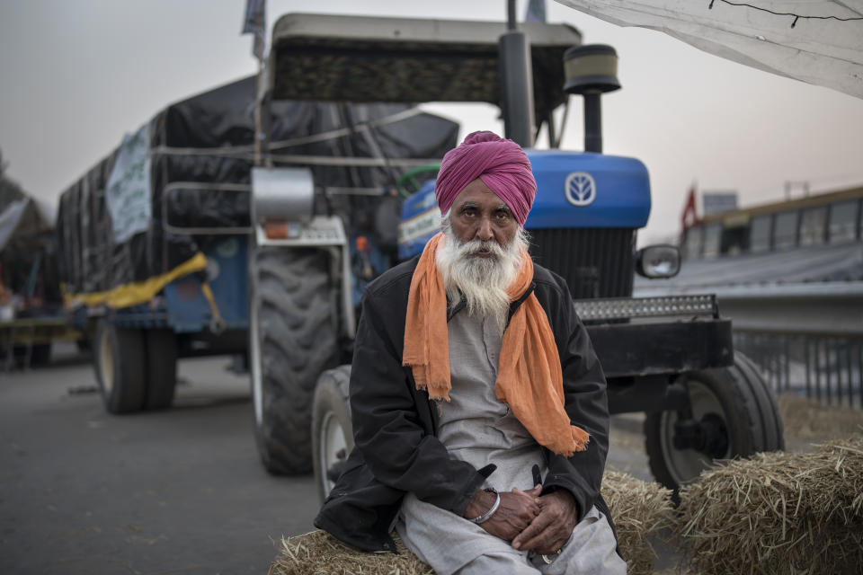 Farmer Atma Singh, 62, poses for a photograph as next to his tractor parked on a highway during a protest at the Delhi-Haryana state border, India, Wednesday, Dec. 2, 2020. The farmers are protesting new laws they say will result in their exploitation by corporations, eventually rendering them landless. Now, they are blocking highways, unwilling to withdraw and threatening to besiege the capital if their demands aren’t met. (AP Photo/Altaf Qadri)