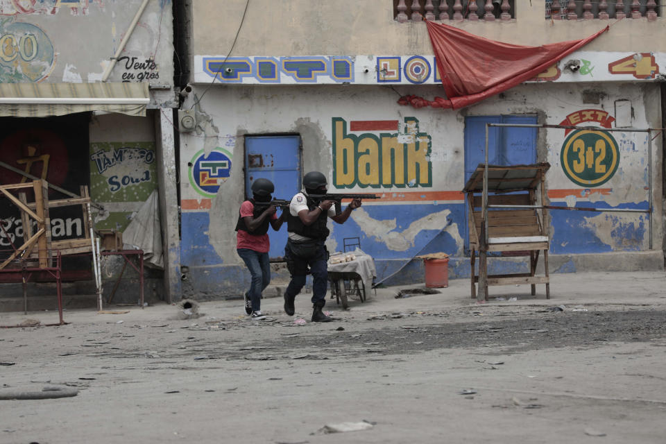 Police officers take cover during an anti-gang operation in the Portail neighborhood of Port-au-Prince, Haiti, Tuesday, April 25, 2023, a day after a mob in the Haitian capital pulled 13 suspected gang members from police custody at a traffic stop and beat and burned them to death with gasoline-soaked tires. (AP Photo/Odelyn Joseph)