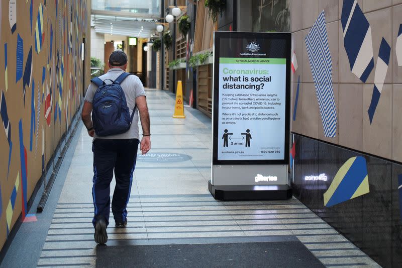 A man walks in a corridor near a sign with instructions about the coronavirus and social distancing following the implementation of stricter social-distancing and self-isolation rules to limit the spread of the coronavirus disease (COVID-19)