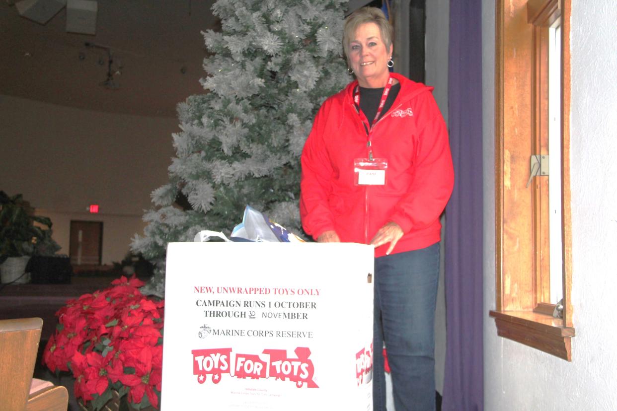 Pam Bognar, the Hillsdale County coordinator for the United States Marine Corps Toys for Tots program, poses for a photo with a toy collection box Nov. 17.