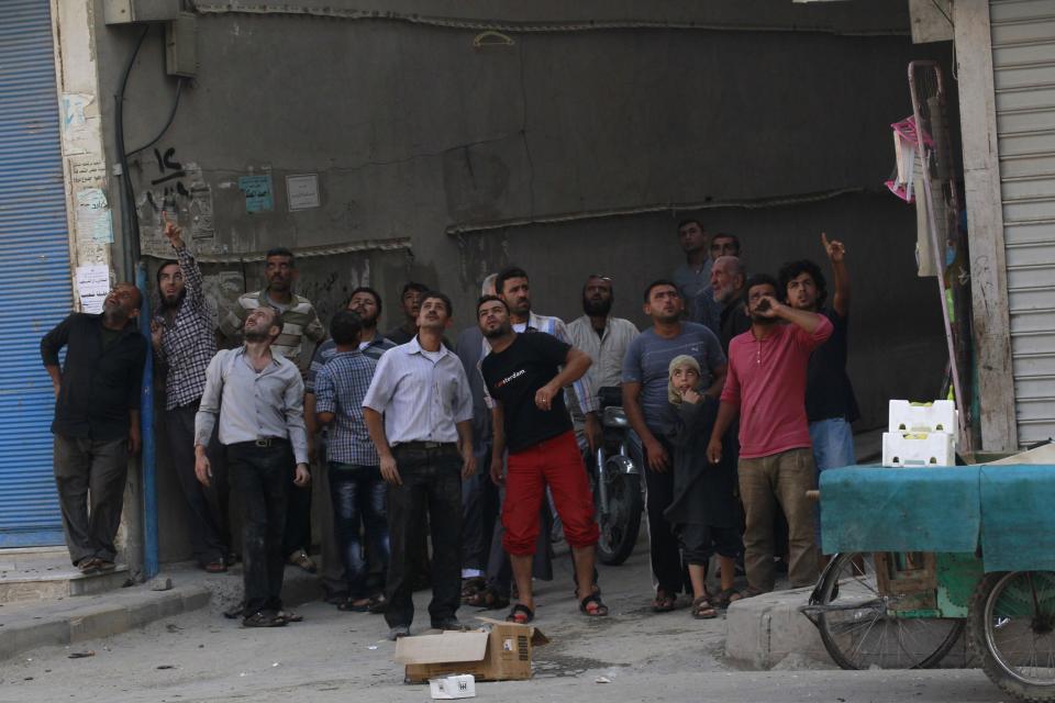 Residents search the sky for warplanes of forces loyal to Syria's President Assad in central Raqqa