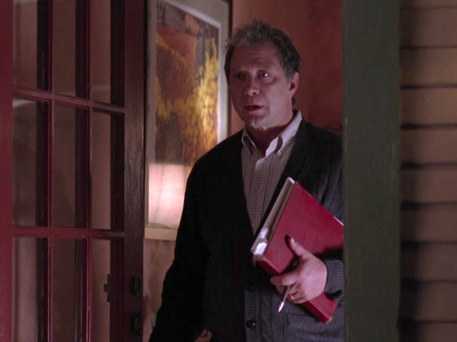 Jeff Perry as Thatcher on Greys Anatomy, standing in a door way holding a folder while wearing a cardigan