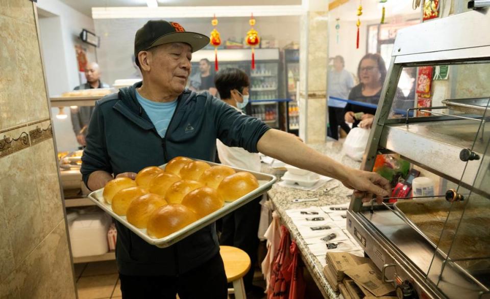 Owner Yao Li fills a warming bin with freshly baked cha sui bao, his most popular item at Lam Kwong Deli & Market, on March 20, 2024. They make more than 700 a day on weekdays and nearly 1,000 on Saturday.