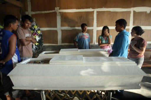 Residents look at the coffins of those killed in the landslides that buried mining tunnels and tents in the gold-rich town of Pantukan, Compostela Valley, in the Philippines. Philippine officials say there is little chance of finding more survivors, with 22 people likely killed in the disaster