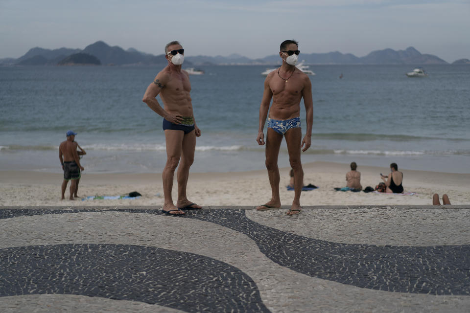 Jesus Costa and Antonio Ancon, right, stand on Copacabana beach amid the outbreak of the new coronavirus in Rio de Janeiro, Brazil, Sunday, July 12, 2020. "I prefer to have tan lines on the face than to put my life at risk" says Ancon about the use of the face masks at the beach as a measure to curb the spread of the new coronavirus. (AP Photo/Leo Correa)