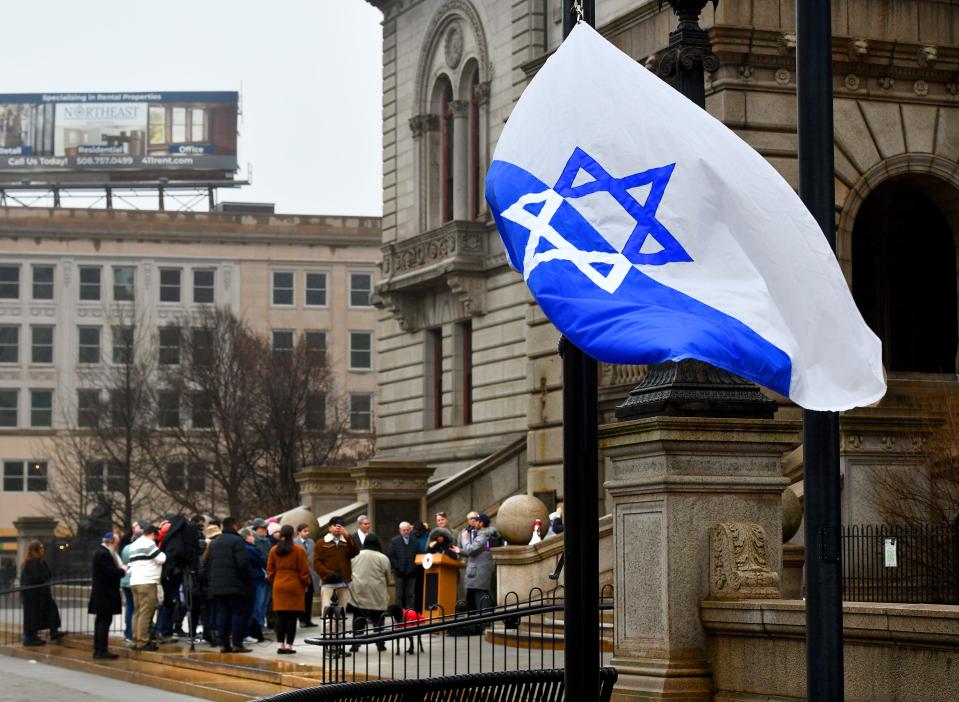 People gather at City Hall Friday to commemorate International Holocaust Remembrance Day and to raise a flag for the Warsaw ghetto uprising.