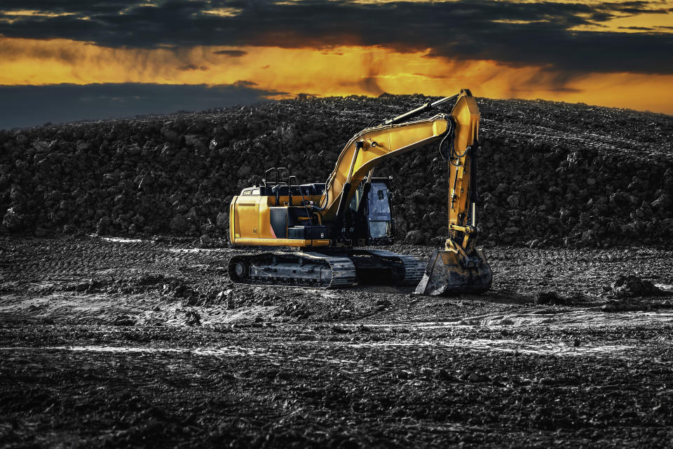 Excavator. Earth-Moving Heavy Equipment Construction side. Excavator on the construction side with a pile of land on the background. An Excavators are heavy construction equipment consisting of a boom, dipper, bucket and cab on a rotating platform known as the house.
