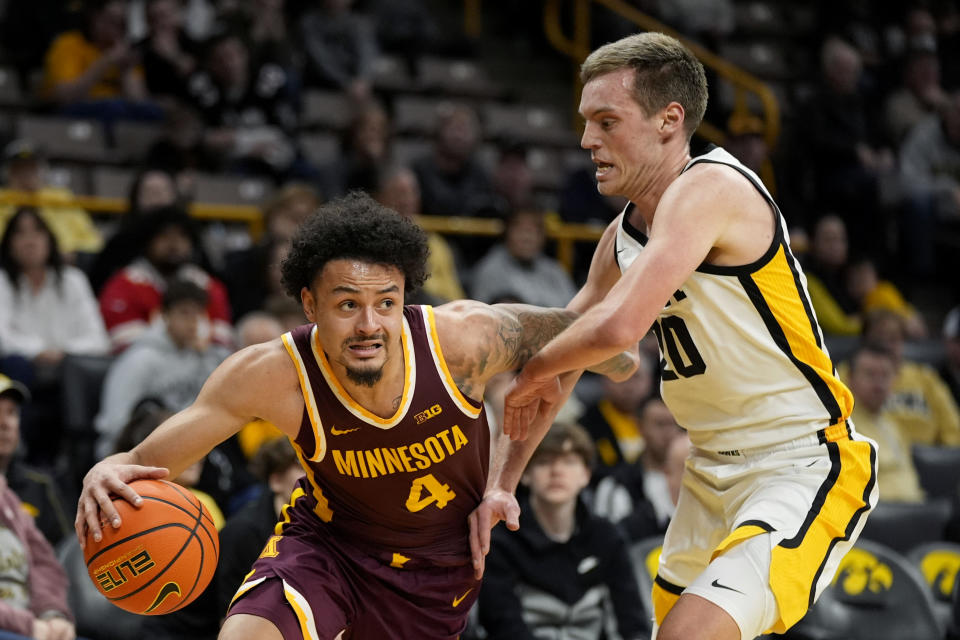 Minnesota guard Braeden Carrington (4) drives past Iowa forward Payton Sandfort (20) during the first half of an NCAA college basketball game, Sunday, Feb. 11, 2024, in Iowa City, Iowa. (AP Photo/Charlie Neibergall)