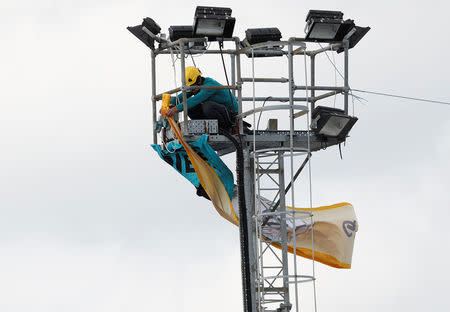 A Greenpeace activist tries to unfurl a banner from a lighting tower after activists entered the vehicle park in a protest against Volkswagen diesel vehicles at the port of Sheerness, Britain, September 21, 2017. REUTERS/Peter Nicholls