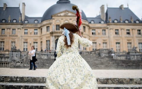 A woman wearing a costume visits the Vaux-Le-Vicomte castle during the "Great Century Day" in Maincy, outside Paris, France in July, 2015 - Credit: &nbsp;Kamil Zihnioglu/AP