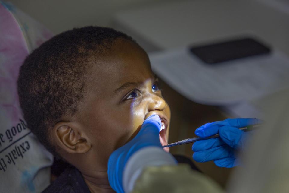 A hygienist cleans a child's teeth.