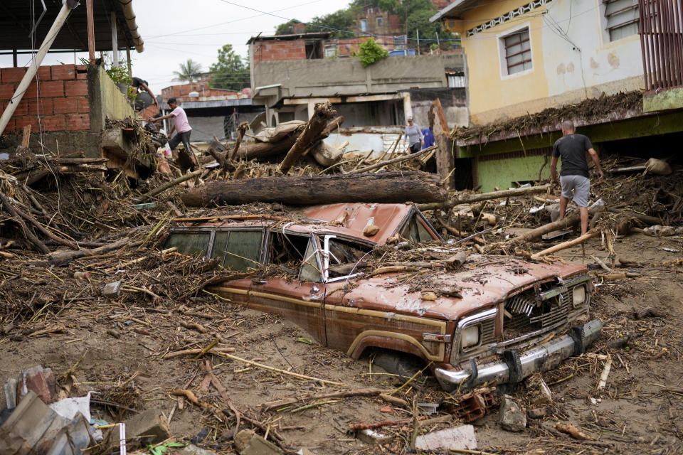 Residents walk through the debris left by flooding caused by a river that overflowed after days of intense rain in Las Tejerias, Venezuela, Sunday, Oct. 9, 2022. (AP Photo/Matias Delacroix)